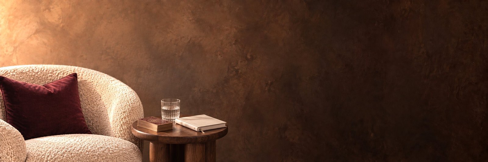 Un sillón de tela clara junto a una mesa baja con un mazo de cartas y un cuaderno.